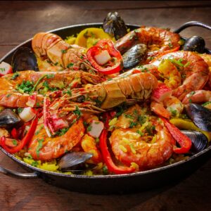 A vibrant and flavorful seafood paella served in a pan with mussels and shrimp.